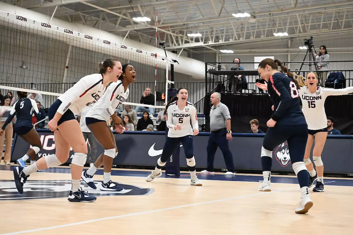 Volleyball players celebrate as the Huskies win their final game of the season against Villanova.
