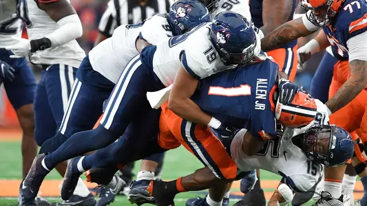 Connecticut linebacker Langston Hardy (19) and linebacker Tui Faumuina-Brown (15) tackle Syracuse running back LeQuint Allen (1) during the first half of an NCAA football game on Saturday, Nov. 23, 2024 in Syracuse, N.Y.