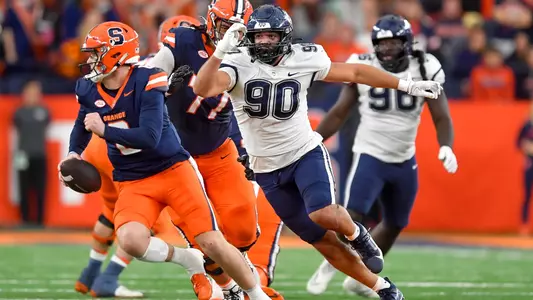 Connecticut defensive lineman Pryce Yates (90) pressures Syracuse quarterback Kyle McCord (6) during the first half of an NCAA football game on Saturday, Nov. 23, 2024 in Syracuse, N.Y.