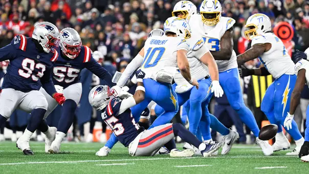 Jan 11, 2026; Foxborough, MA, USA; Los Angeles Chargers quarterback Justin Herbert (10) fumbles after a hit by New England Patriots cornerback Marcus Jones (25) during the third quarter in an AFC Wild Card Round game at Gillette Stadium. Mandatory Credit: Eric Canha-Imagn Images