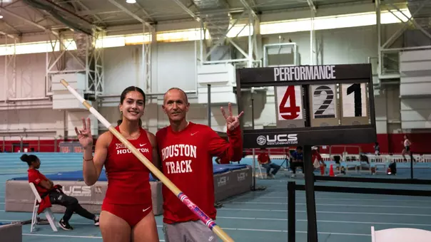 Evina Panagiotou stands next to sign reading 4.21m with Kyle Tellez after setting the indoor pole vault school record