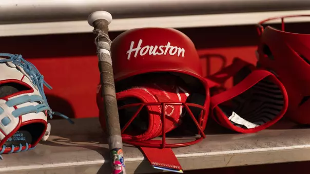 softball helmet that reads "Houston" sitting on a shelf with batting gloves