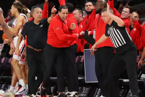 Houston student-athletes and coaches cheer on the sideline during a Men's Basketball game.