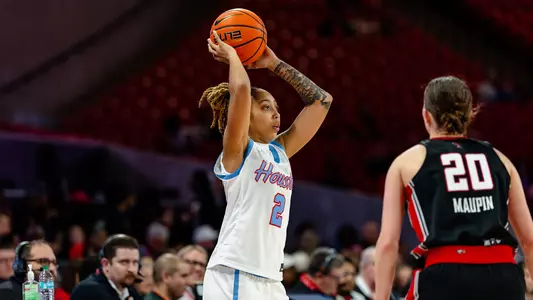 kierra merchant getting ready to throw basketball over her head with texas tech opponent in front of her