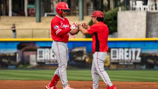 Blake Fields pumps fists with first base coach Matthew Whitting after reaching base against Alabama.