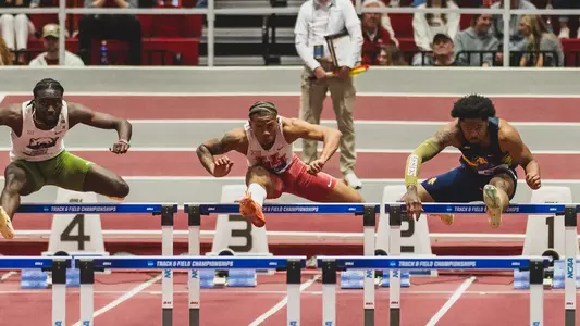 Jamar Marshall Jr. (center) jumping over hurdle at 2026 NCAA Indoor Championships