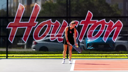 sophie schouten prepares to serves in front of a net that reads HOUSTON