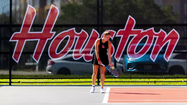 sophie schouten prepares to serves in front of a net that reads HOUSTON