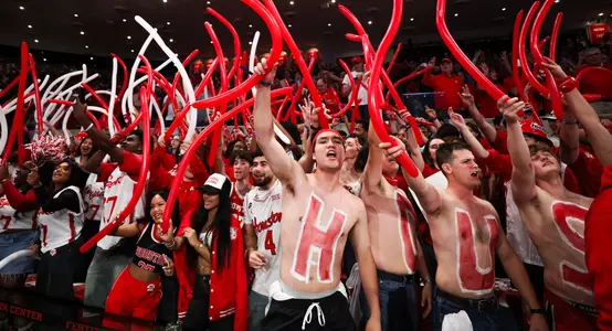 Students cheer with balloons during a game inside Fertitta Center