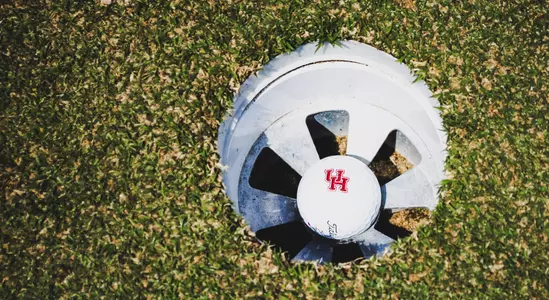 A Houston golf ball rests in a hole
