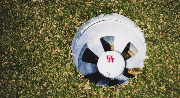 A Houston golf ball rests in a hole