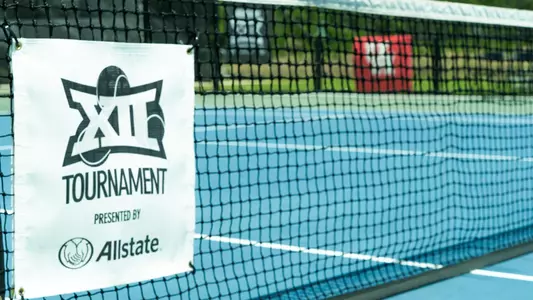signage that reads Big 12 Tennis Tournament hanging on a tennis net