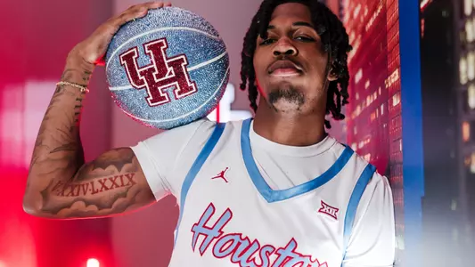 Corey Hadnot II leads against a wall with a blue glittered UH Basketball