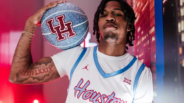 Corey Hadnot II leads against a wall with a blue glittered UH Basketball