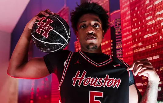 Braden East pops his black HOuston jersey while holding a glittered basketball