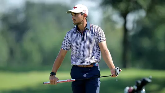 Hudson Weibel preparing to putt on green with putter in his hands