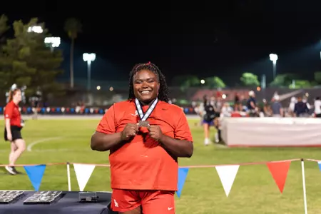 Sydney Freeman smiling and holding big 12 silver medal
