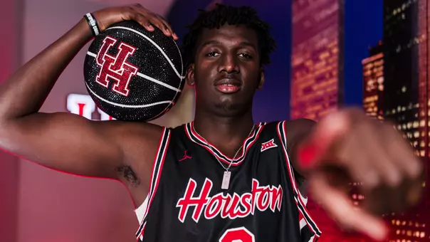 Djafar Silimana holds a glittered basketball, flexes and points