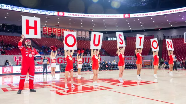 Fan and cheerleaders holding up letters that spell out Houston