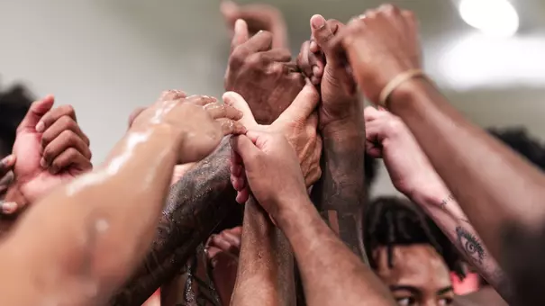 The Cougars join hands in a team huddle following a workout