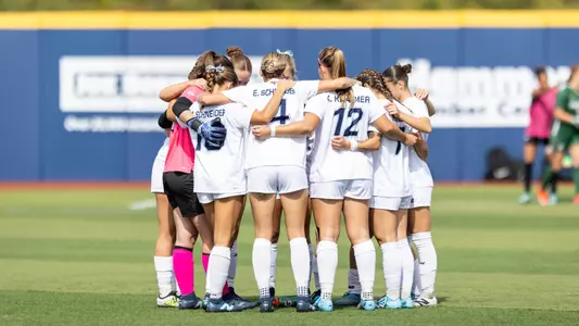 Maine women's soccer huddles on the field.