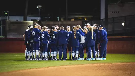 Maine softball huddles in the outfield.