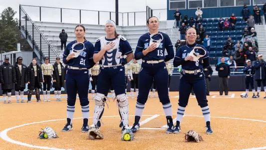 Maine softball stands on the field during the national anthem.