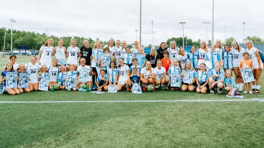 Maine women's soccer poses with young fans.