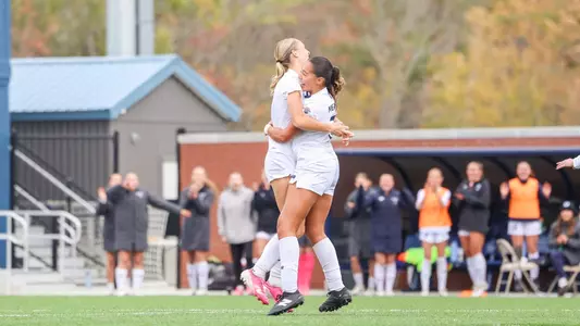 Victoria Dungey and Isabella Meadows celebrate a goal.