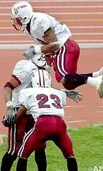 Massachusetts' Lamarr Monterio and Shannon James, in air, congratulate Anton McKenzie after his interception return for a touchdown against New Hampshire in the first period.