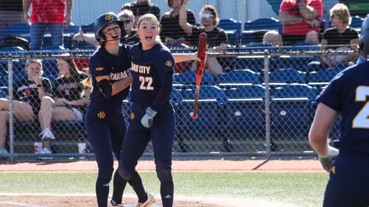 Ella Husak and Lauren Parker celebrate after Husak slides safely into home on an inside-the-park home run