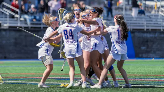 Women's lacrosse group celebration around Pompei after game winning goal in OT over UMBC