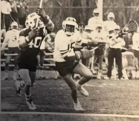 lacrosse player running by defender