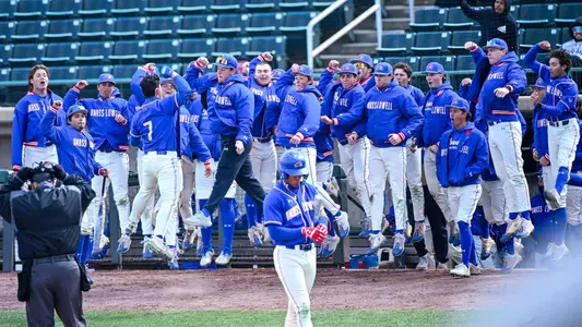 UMass Lowell baseball players celebrating by jumping up together in front of the dugout after one of their teammates hit a home run