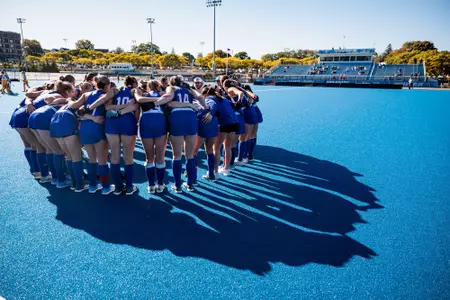Field Hockey team huddling on blue field