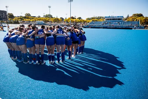 Field Hockey team huddling on blue field