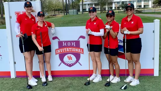 Women's Golf Team standing in front of Icon Invitational Banner with drivers in Hand