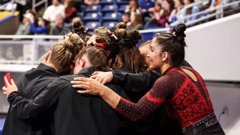 Teammates hug Tasha Brozowski after her bars routine at 2023 NCAA Regionals