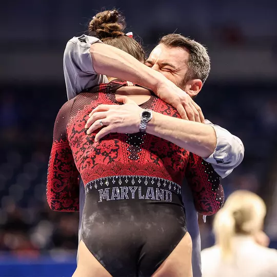 Brett Nelligan hugs Tasha Brozowski after her bars routine at 2023 NCAA Regionals