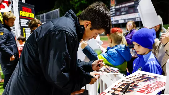 Luke van Heukelum signing an autograph for a fan at Ludwig Field
