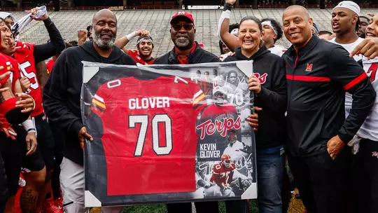 Coach Mike Locksley and AD Damon Evans presenting Kevin Glover with a framed jersey for his retirement