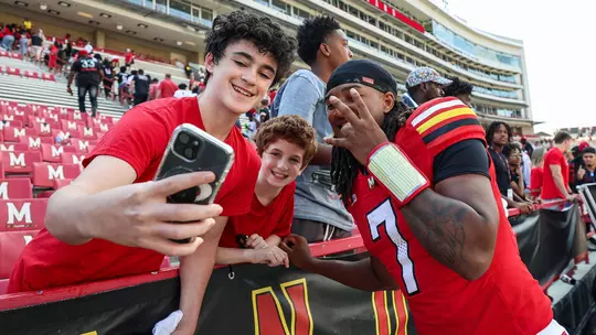 Malik Washington posing for a photo with Terrapin fans after a game.
