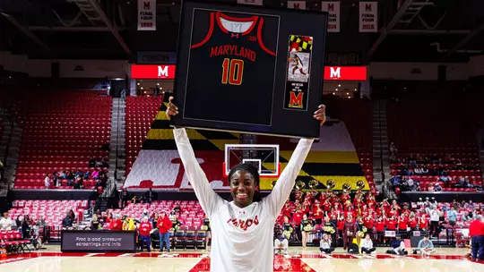 Mir McLean holding up her framed jersey on Senior Day
