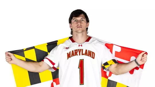 Studio photo of Eric Spanos with the Maryland flag in his hands spread behind his shoulders