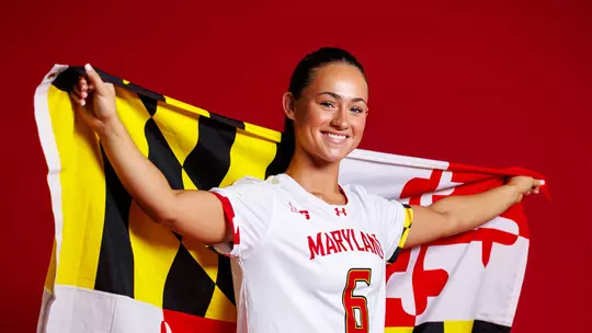 Studio photo of Keeley Block holding a Maryland flag on a red backdrop