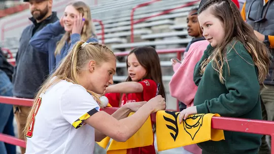 Lauren LaPointe signing an autograph for a young Terps fan after a game at SECU Stadium