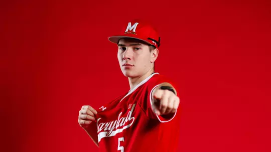 Studio photo of Ty Kaunas pointing on a red backdrop