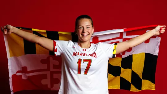 Studio photo of Maddy Sterling holding a Maryland flag on a red backdrop
