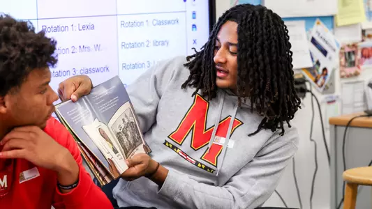 Maryland QB Malik Washington reading to children at an elementary school