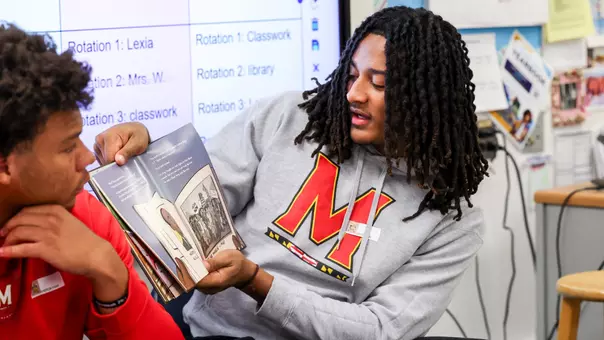 Maryland QB Malik Washington reading to children at an elementary school